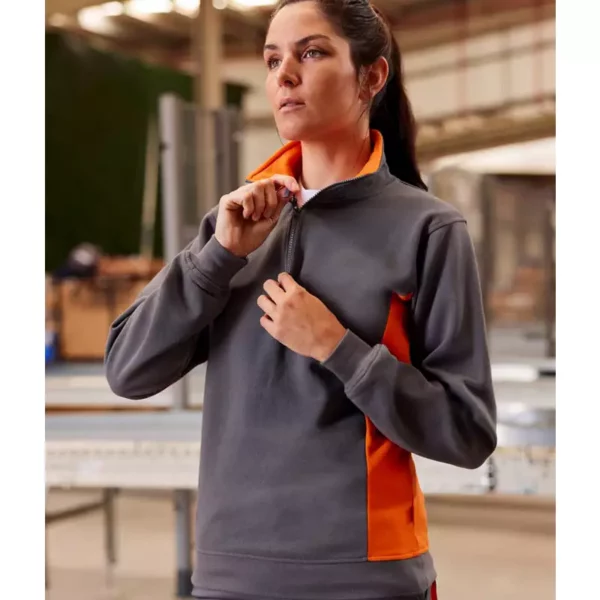 Mujer vistiendo una sudadera bicolor, gris y naranja, con cremallera Velilla 105704 en un entorno de trabajo