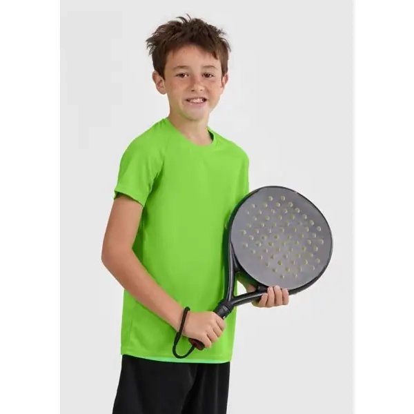 Camiseta infantil Mukua TECH KIDS MK521V 1 Niño con camiseta técnica Mukua TECH KIDS MK521V lima flúor y una pala en la mano.