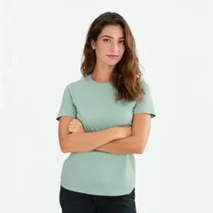 Mujer con camiseta Mukua PALM WOMAN TS190WC verde salvia, con los brazos cruzados.