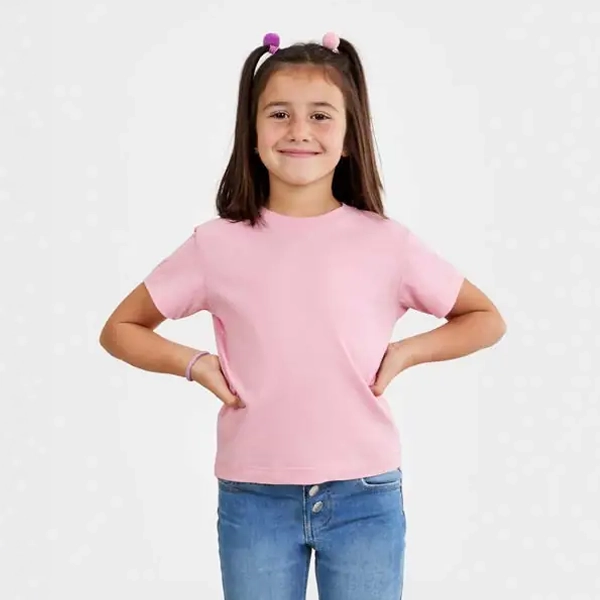Camiseta infantil Mukua COAST KIDS TSN165KC 1 Niña con camiseta Mukua COAST KIDS TSN165KC rosa de manga corta y las manos en la cintura.