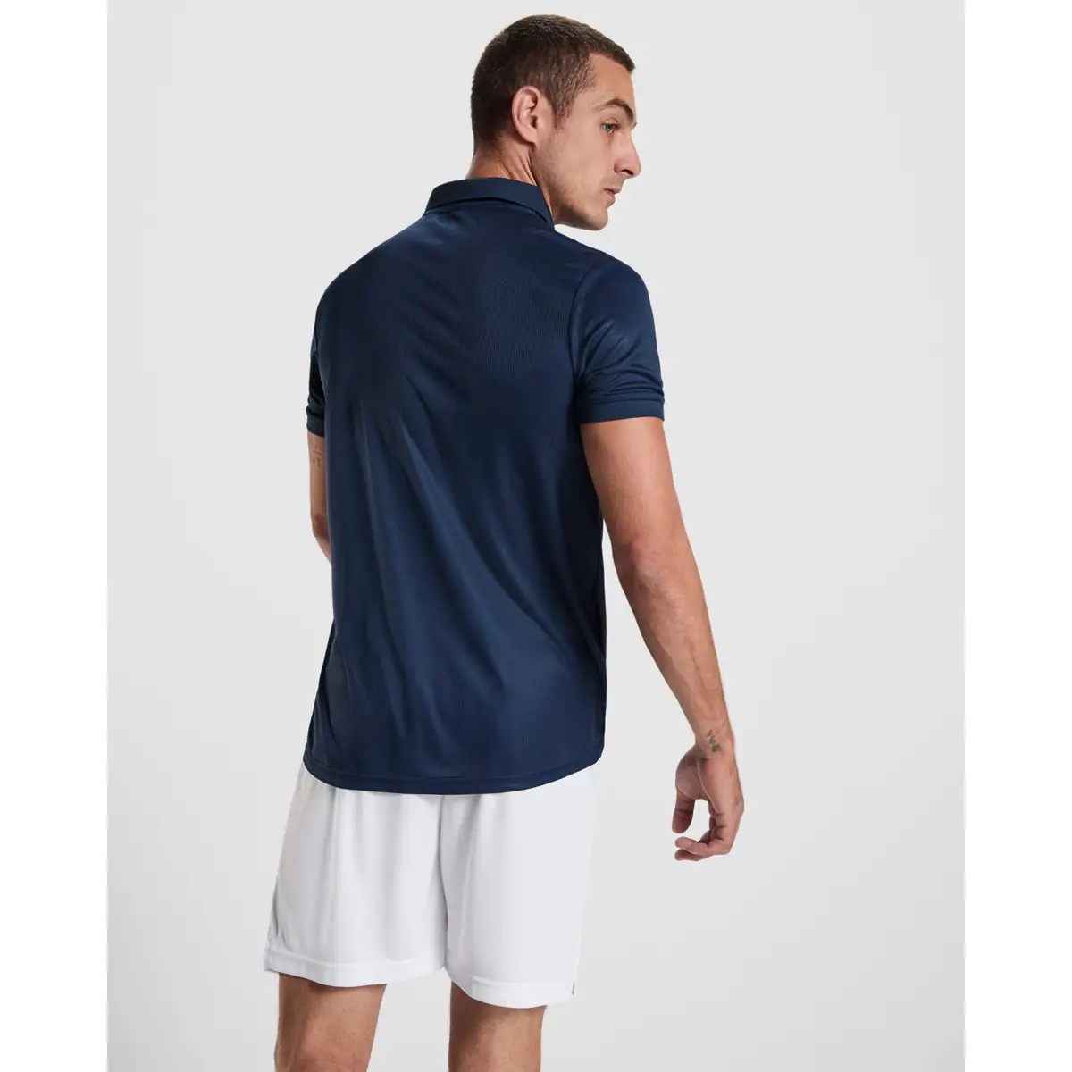 Polo técnico reciclado hombre Roly TORMO 2 Polo Roly TORMO en azul marino, vista trasera con modelo