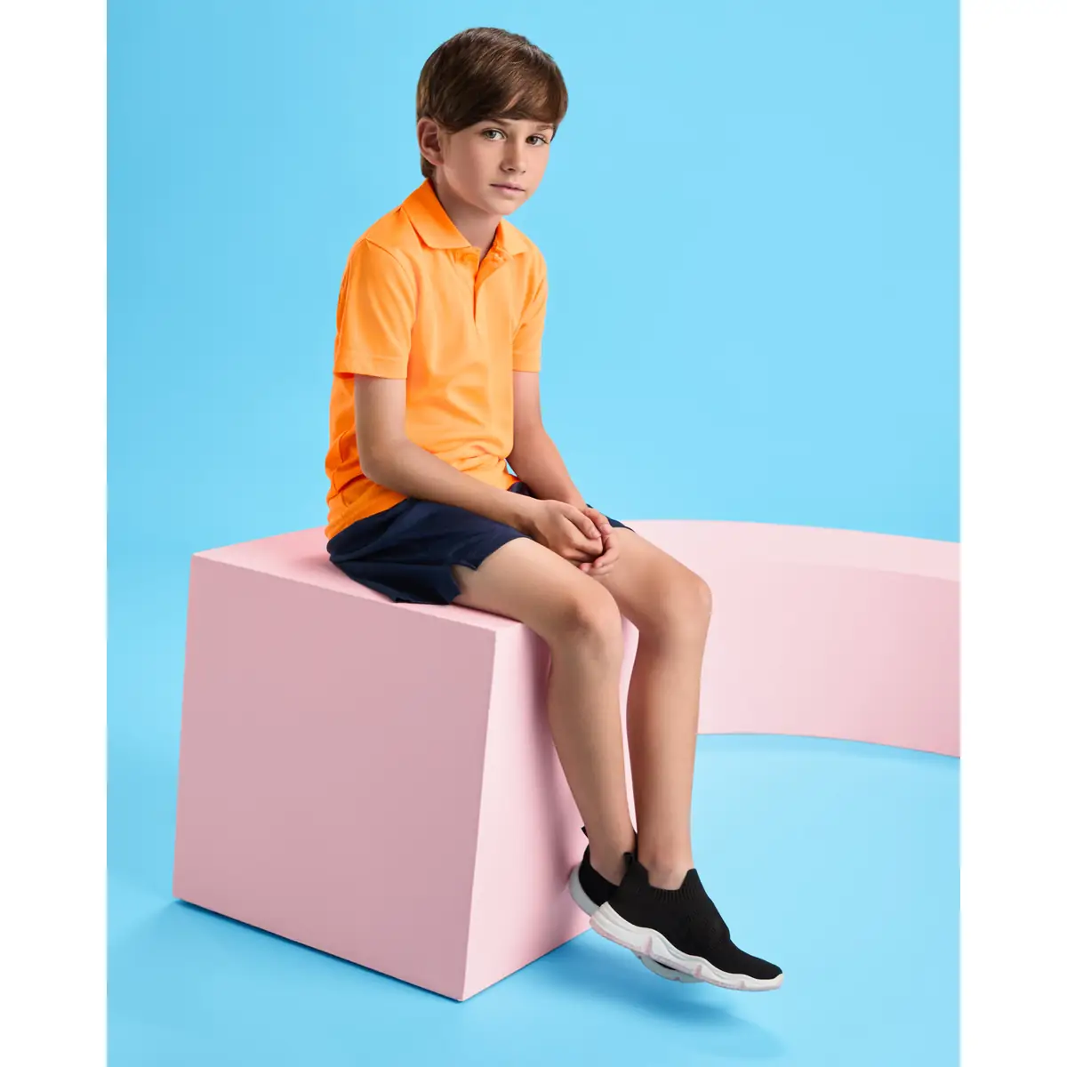 Polo técnico transpirable Roly MONZHA 2 Polo Roly MONZHA en naranja flúor, vista frontal con modelo infantil