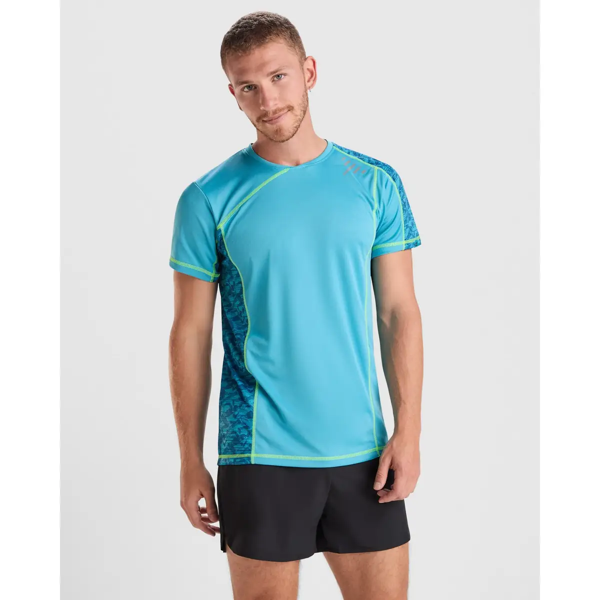 Camiseta técnica Hombre Roly SOCHI 1 Camiseta Roly 0426 de manga corta en turquesa con detalles verde lima, vista frontal sobre un modelo.