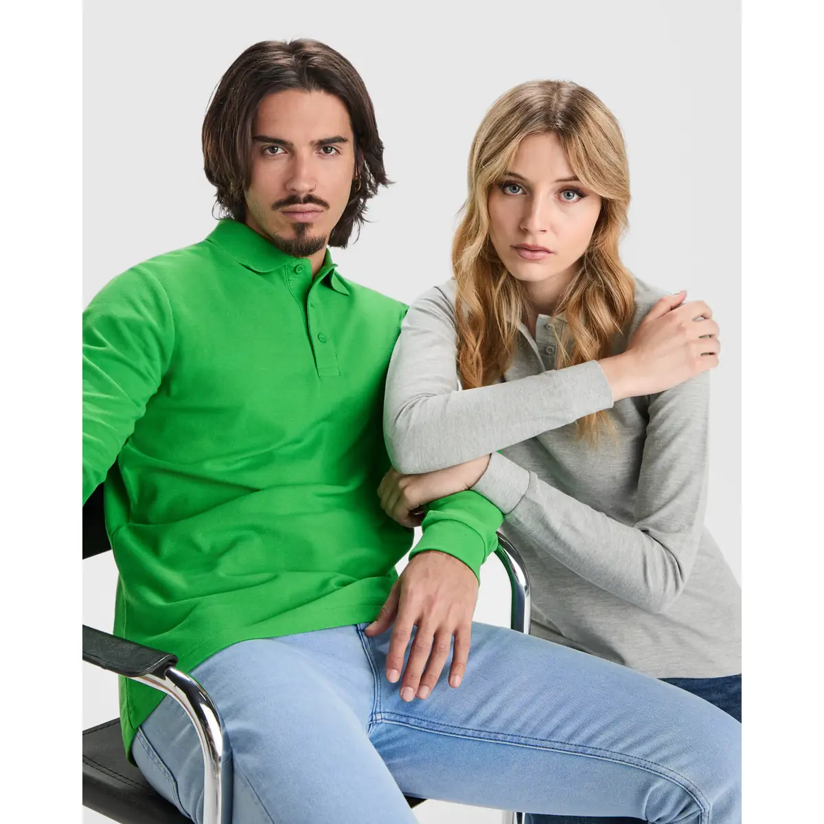 Polo piqué manga larga Roly ESTRELLA L/S 9 Polo Roly ESTRELLA L/S en verde grass de manga larga, junto a un polo femenino gris, modelos sentados