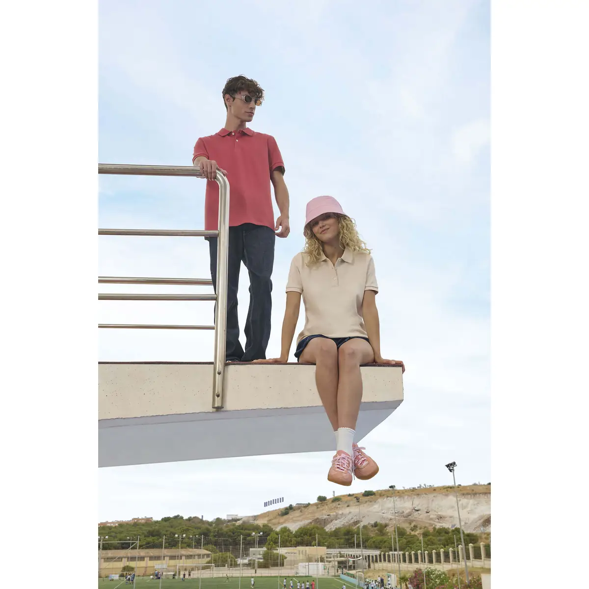 Polo mujer SOL’S PACIFIC WOMEN 04440 9 Polo Sol’s PACIFIC WOMEN beige, vestido por una modelo sentada junto a un modelo con polo granate