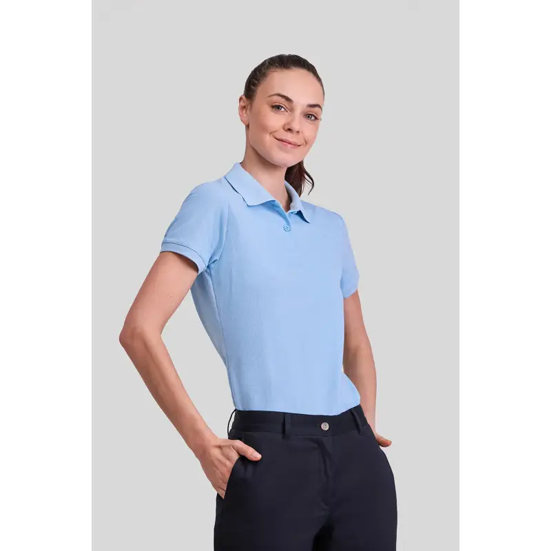 Polo básico de mujer Norvil MILAN 4 Polo básico de mujer Norvil MILAN en azul celeste, vista frontal, sobre modelo.