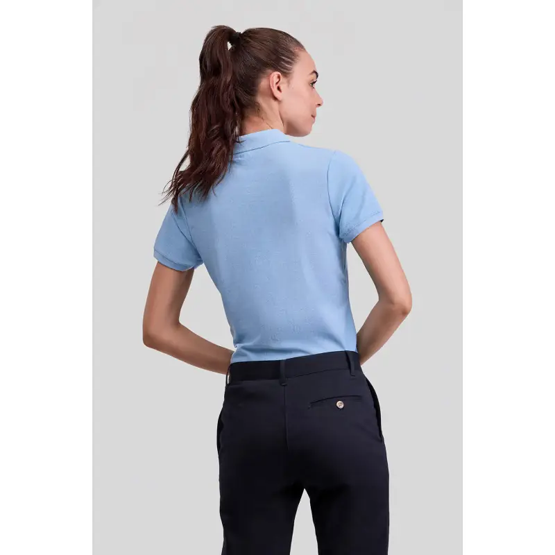 Polo básico de mujer Norvil MILAN 5 Polo básico de mujer Norvil MILAN en azul celeste, vista trasera, sobre modelo.