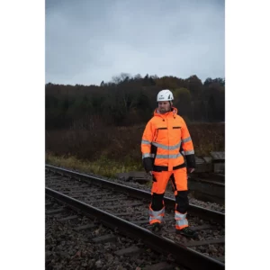 Prendas PROJOB de color naranja, vista frontal con modelo en entorno ferroviario