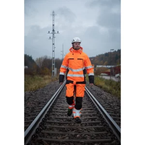Prendas PROJOB de color naranja, vista frontal con modelo en entorno ferroviario