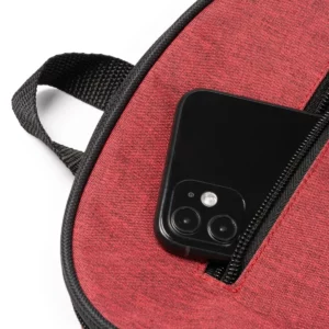 Mochila de RPET Stamina Bamba 1672, rojo vigoré, detalle del bolsillo frontal con un teléfono como ejemplo de uso