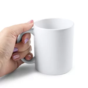 Taza de cerámica para sublimar Stamina Lima 4000, blanco, vista de una mano sujetando la taza por el asa