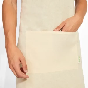 Una unidad del pack de 10 delantales orgánicos Stamina Oliver 9135, crudo, detalle del bolsillo frontal con modelo